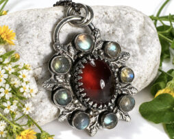 Nahaufnahme von floralem Silberschmuck mit schillernden Labradorit Edelsteinen und rotem Granat