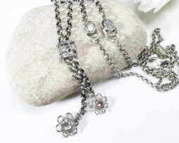 Diese elegante Y-Halskette aus hochwertigem 925 Sterling Silber vereint filigranes Design mit hochwertigen Edelsteinen. Zarte Blumenmotive zieren die Kette und sind mit funkelnden Steinen besetzt: strahlender Moissanit für ein funkelndes Highlight, sanfter Rosenquarz für eine feminine Eleganz und pink Turmalin als lebendiger Farbakzent. Die Hauptkette misst eine Länge von 45 cm, ohne das Schmuckelement mit eingerechnet. Das dekorative Anhänger-Element, bestehend aus zwei filigranen Blumen, hat eine zusätzliche Länge von 5 cm. Alle Silberteile wurden sorgfältig geschwärzt und anschließend poliert, um ihnen einen edlen, antiken Look zu verleihen.