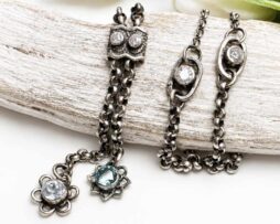 Diese elegante Y-Halskette aus hochwertigem 925 Sterling Silber vereint filigranes Design mit hochwertigen Edelsteinen. Zarte Blumenmotive zieren die Kette und sind mit funkelnden Steinen besetzt: strahlender Moissanit für ein funkelndes Highlight, sanfter Aquamarin für eine feminine Eleganz und Swiss blauer Topas als lebendiger Farbakzent. Die Hauptkette misst eine Länge von 45 cm, ohne das Schmuckelement mit eingerechnet. Das dekorative Anhänger-Element, bestehend aus zwei filigranen Blumen, hat eine zusätzliche Länge von 5 cm. Alle Silberteile wurden sorgfältig geschwärzt und anschließend poliert, um ihnen einen edlen, antiken Look zu verleihen.