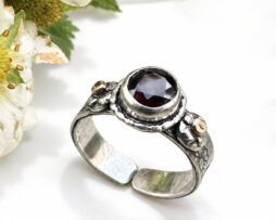 Aufrecht stehender Bicolor Silberring mit rotem Mosambik Granat und filigranen Golddetails.