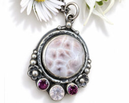 Handgefertigter Designer-Blumenanhänger aus Silber mit rundem rosa Larimar auf hellem Hintergrund.