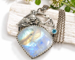 Handgefertigter Eulen-Anhänger aus 935er Silber mit einem großen, blau schimmernden Regenbogen-Mondstein und einem kleinen Swiss Blue Topas an einer Silberkette.